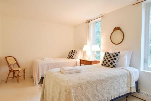 a white room with two beds and a chair at Short Walk to Long Pond Swimming Beach in Wellfleet