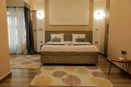 een slaapkamer met een groot bed en een tapijt bij Meirah Gardens Naivasha in Naivasha