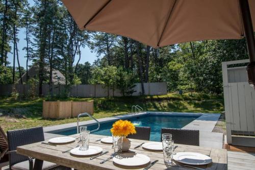 a table with chairs and an umbrella next to a pool at Private Pool and Close to Marconi Beach in Wellfleet