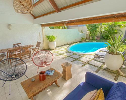 une terrasse avec un canapé, une table et une piscine dans l'établissement *New* Chic Home with Private Pool, 1 min to Beach, à Cap Malheureux
