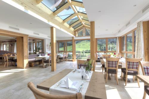 una sala da pranzo con tavoli, sedie e finestre di Hotel Traube a Pettneu am Arlberg