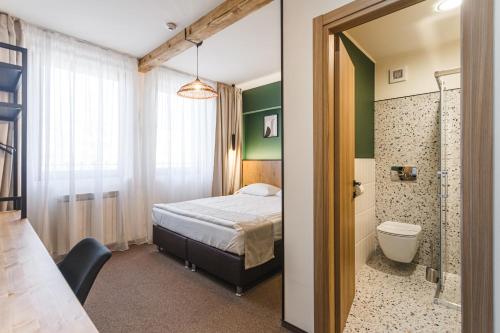 a bedroom with a bed and a bathroom with a toilet at Stokker Hotel in Oradea