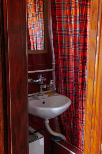 a bathroom with a sink and a plaid shower curtain at Domacinska kuca in Bajina Bašta