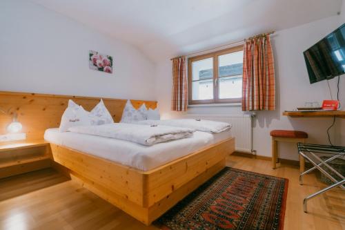 a bedroom with a wooden bed in a room at Hotel-Pension Faneskla in Silbertal