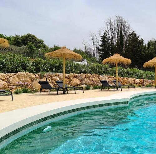 una piscina con sombrillas y sillas y una piscina en Cortijo Rancho Verde, en Colmenar