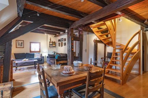 un salon avec une table en bois et un escalier en colimaçon dans l'établissement Les Gîtes Coeur de Vigne, à Riquewihr