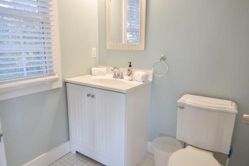 a white bathroom with a toilet and a sink at Waterfront Fun at this Huge Family Estate in Eastham