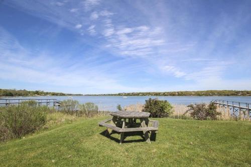 a picnic table sitting on the grass near the water at Waterfront Fun at this Huge Family Estate in Eastham
