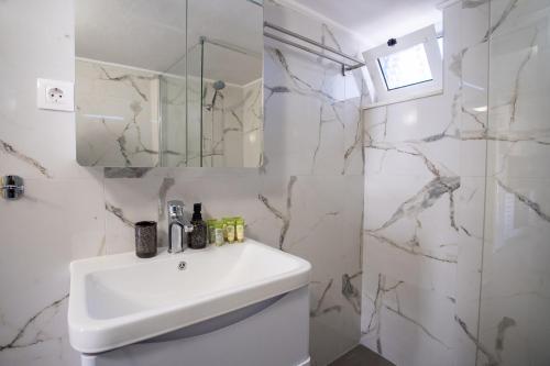 a white bathroom with a sink and a mirror at Two Bedroom Apartment, Mytilene Lesvos in Mytilini