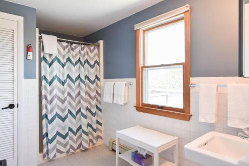 Un baño con cortina de ducha y lavabo. en Steps to Private Association Beaches, en Eastham
