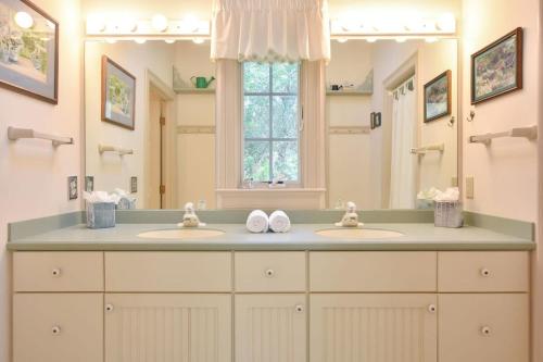 La salle de bains est pourvue de 2 lavabos et d'un grand miroir. dans l'établissement Walk to Water Hot Tub & Game Room, à Eastham