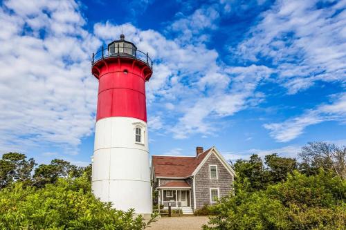 a red and white lighthouse in front of a house at Minutes to Private Association in Eastham