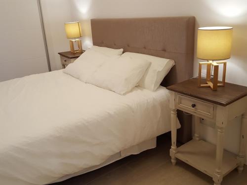 - un lit avec des draps blancs et une table de chevet avec deux lampes dans l'établissement Mandala apARTments, à Calafell