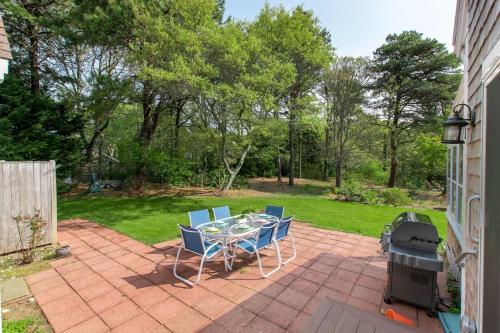 a patio with a table and chairs and a grill at Sunroom Mins to Beaches Views of Marsh in Eastham