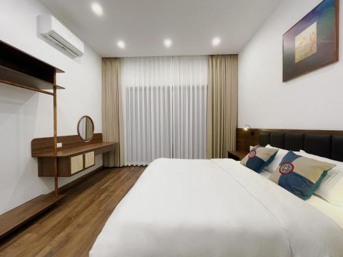 a bedroom with a large white bed and a desk at Bản Nhỏ - Little Village in Cao Bằng