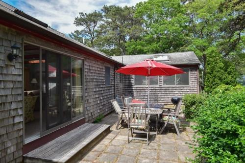 a patio with a table and chairs and an umbrella at Spacious Home w Finished Game Room in Eastham