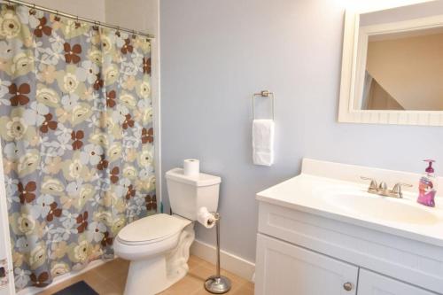 y baño con aseo y cortina de ducha. en Newly updated spacious steps to water, en Eastham