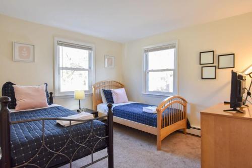 a bedroom with a bed and a couch and two windows at 14482 - Exceptional Home with Backyard Oasis Close to Great Pond Bay and Ocean Beaches in Eastham