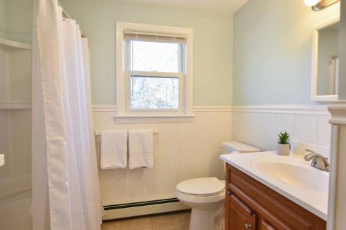 a bathroom with a toilet and a sink and a window at 14482 - Exceptional Home with Backyard Oasis Close to Great Pond Bay and Ocean Beaches in Eastham