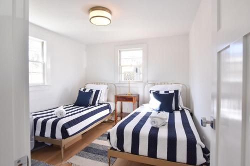 2 Betten in einem weißen Zimmer mit blauen und weißen Streifen in der Unterkunft Newly Renovated Cottage on Town Cove in Eastham