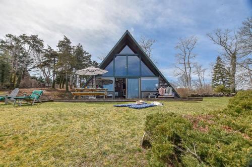 a house with a thatched roof on a grass field at Dream Waterfront A-Frame in Orleans in Orleans
