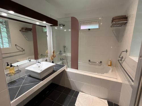 La salle de bains est pourvue d'un lavabo, d'une baignoire et d'une douche. dans l'établissement Bungalow Terra - Sarramea, à Sarraméa