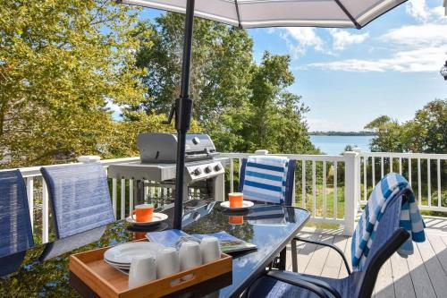 una mesa y sillas en una terraza con sombrilla en 15526 - Luxurious Waterfront Home with Incredible Entertainment Space Secluded on Pleasant Bay, en Orleans