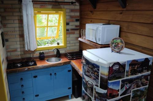 uma cozinha com um lavatório e um micro-ondas em Chalé do Vale Pomerode em Pomerode