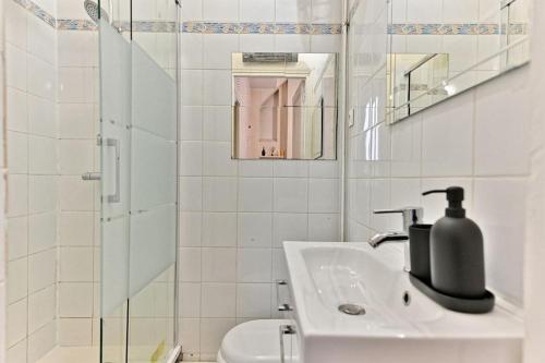une salle de bain blanche avec un lavabo et une douche dans l'établissement Appartement Rez-de-chaussée Paris - Montparnasse, à Paris
