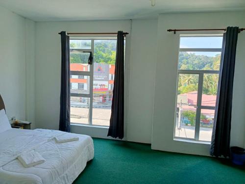 a bedroom with a bed and two large windows at HASD GUESTHOUSE PANGKOR in Pangkor