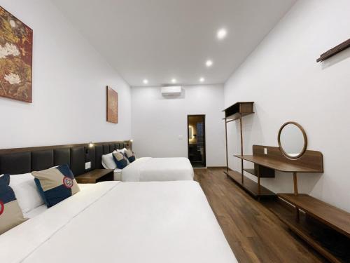 a hotel room with two beds and a desk at Bản Nhỏ - Little Village in Cao Bằng