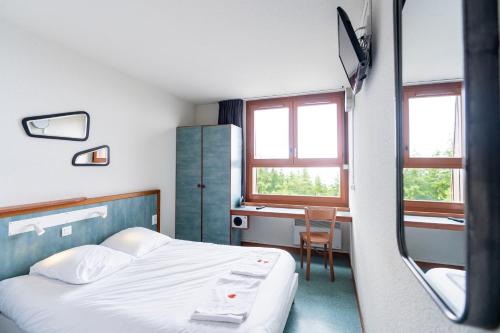 a bedroom with a bed and a desk and window at Villages Clubs du Soleil - LES KARELLIS in Montricher-Albanne