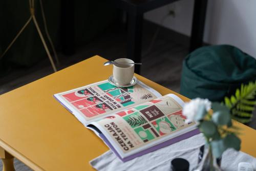 - un journal sur une table avec une tasse en haut dans l'établissement Cozy Studio Retro in Poznan by Renters, à Poznań