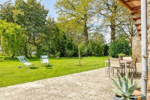a patio with chairs and a table in a yard at Le Kerhuel d' Agnès in Plouasne