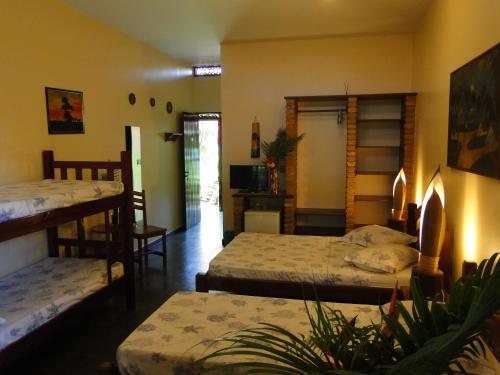 a bedroom with two beds and a living room at Hotel Pousada Arco Iris in Barra de Santo Antônio
