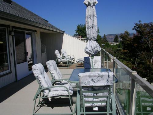 a table with chairs and an umbrella on a balcony at Casa Loma BnB in West Kelowna