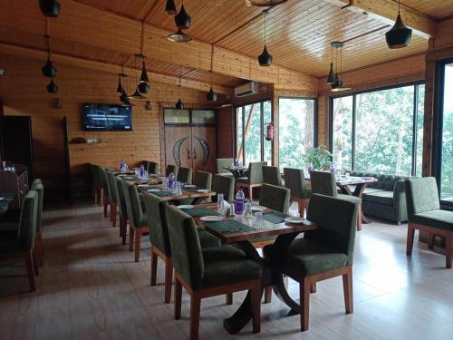 uma sala de jantar com mesas longas e cadeiras verdes em Ri Shat Orchid Resort em Shillong