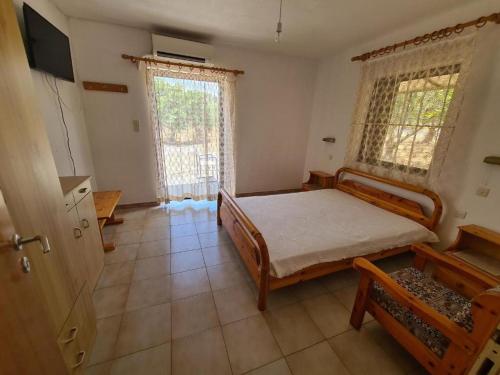 1 dormitorio con 1 cama y 2 ventanas en Το Κτήμα της Ελιάς του Τάκη, en Paralia Demonias