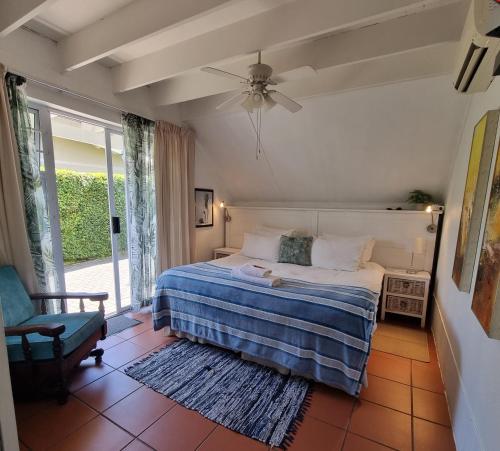 a bedroom with a bed and a chair and a window at Nahoon Bed & Breakfast in East London