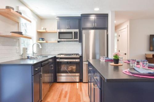 a kitchen with stainless steel appliances and black cabinets at Fully Updated Home w Great Outdoor Space in Chatham