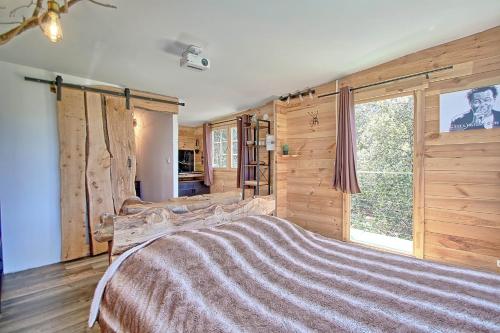 - une chambre avec un grand lit et une grande fenêtre dans l'établissement Sublime cabane perchée clim et cinéma vue panoramique - Le Mas des farachess, à Solliès-Toucas