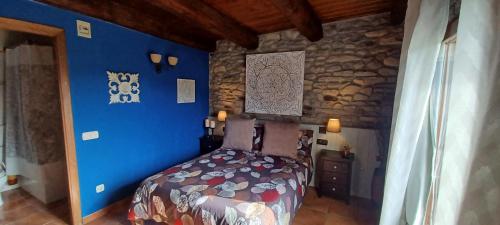 Un dormitorio con una cama con paredes azules y una pared de piedra. en Cimas con historia, en Fiscal