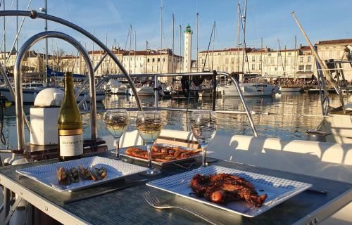 - une table avec deux assiettes de nourriture et des verres de vin dans l'établissement Coriandre 2 - Dormir sur un grand voilier 9 personnes By Nuits au Port, à La Rochelle