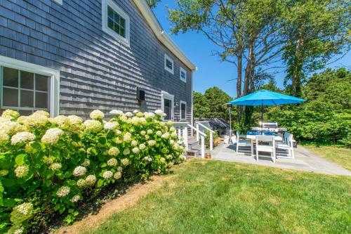 a house with a patio and an umbrella at Walk to Water Access to Hiking Trails! in Harwich
