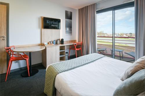 Habitación de hotel con cama, escritorio y mesa. en Kyriad Prestige Residence & Spa Cabourg-Dives-sur-Mer en Dives-sur-Mer