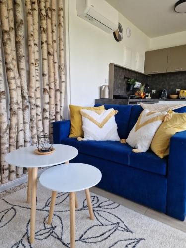 a blue couch with two tables in a living room at Lisi Ogon zanurzeni w naturze in Lisi Ogon