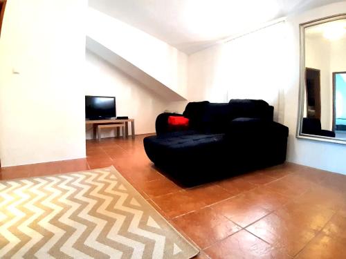 a living room with a black couch and a television at 4 bedrooms apartement with city view balcony and wifi at Porto 3 km away from the beach in Porto