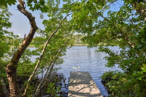 a dock on a lake through the trees at Pond Front Home with Private Dock in Brewster