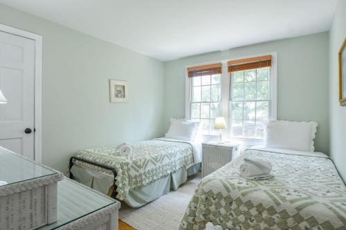 a white room with two beds and a window at Pond Front Home with Private Dock in Brewster