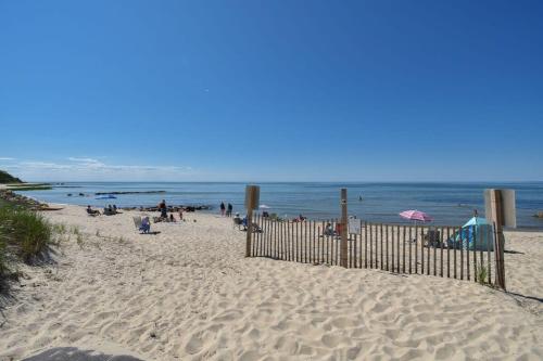 a beach with a fence and people on the beach at Pond Front Home with Private Dock in Brewster